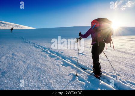 Ein Skitourenreisender, der in den Bergen des Jotunheim in Norwegen in Richtung einer hellen Sonne aufsteigt Stockfoto