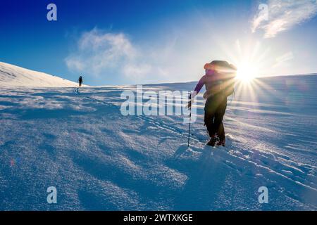 Ein Skitourenreisender, der in den Bergen des Jotunheim in Norwegen in Richtung einer hellen Sonne aufsteigt Stockfoto