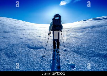 Ein Skitourenreisender, der in den Bergen des Jotunheim in Norwegen in Richtung einer hellen Sonne aufsteigt Stockfoto