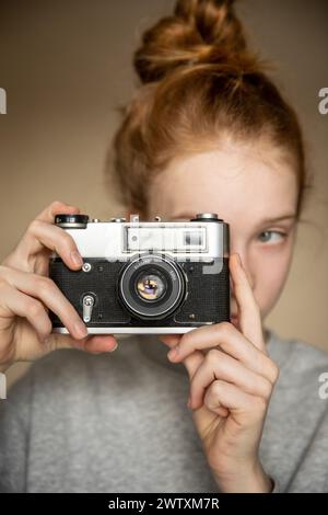 Film-Retro-Kamera in den schönen Händen eines jungen rothaarigen Mädchens Stockfoto