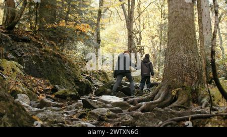 Junge aktive Frau und ihr Sohn wandern, wandern im Wald. Kreativ. Herbstspaziergang auf steinigen Pfaden mit Baumwurzeln. Stockfoto