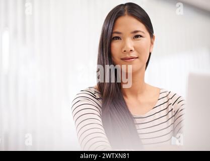 Selbstbewusst, Angestellter und Porträt einer Frau mit Laptop auf dem Tisch, die mit dem Internet arbeitet. Erwachsene, asiatische weibliche Person und Mitarbeiter in der Firma To Stockfoto