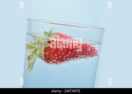 Foto einer Erdbeere in Mineralwasser in einem Glas. Details einer Beere und Wasserblasen aus nächster Nähe. Stockfoto