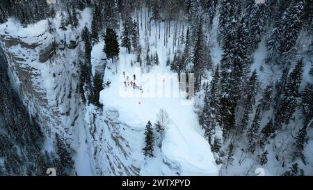 Winterklippe bedeckt mit Schnee, Eis und Pelzbäumen. Clip. Atemberaubende gefrorene Winterlandschaft, aus der Vogelperspektive auf Touristen, die den Tag auf der Klippe genießen Stockfoto