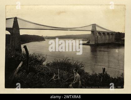 Vintage-Foto der Menai Suspension Bridge eine Hängebrücke, die die Menai Strait zwischen der Insel Anglesey und dem Festland von Wales überspannt. Entworfen von Thomas Telford und 1826 fertiggestellt, war sie die erste große Hängebrücke der Welt, 1880er Jahre, viktorianisches 19. Jahrhundert Stockfoto