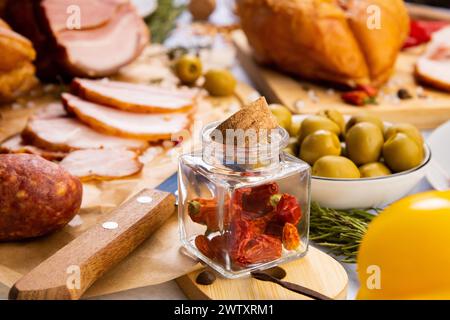 Getrocknete heiße Paprika in einem kleinen Glasgefäß auf dem Tisch, umgeben von Essen Stockfoto