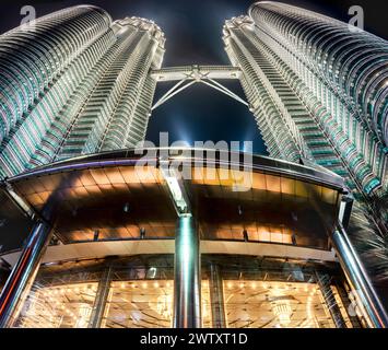 Niedriger Blick auf malaysische Wahrzeichen, beleuchtet in hellem silbrigem Licht vor dem schwarzen Himmel, mit grellen Flutlichtern, Kronleuchtern hängen davon Stockfoto