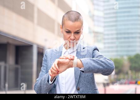 Porträt einer seriösen Geschäftsfrau, die draußen die Zeit auf der Uhr ansieht. Stockfoto