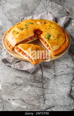 Empanada gallega ist ein traditioneller herzhafter Kuchen aus der spanischen Füllung mit Fleisch, Paprika, Tomaten und Zwiebeln in der Nähe auf dem Brett auf dem Tisch. V Stockfoto