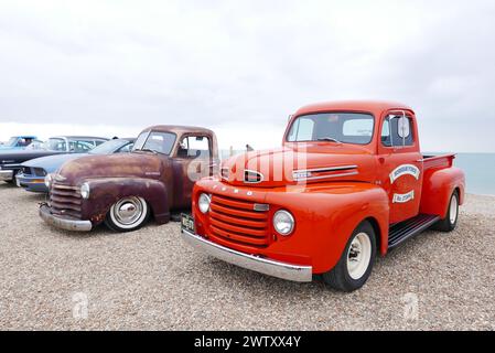 Ein roter 1949 Ford F1 Pickup mit anderen Autos, die am Strand geparkt sind Stockfoto