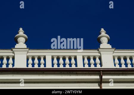 Detail eines eleganten edlen Palastes mit neoklassizistischen Elementen der Balustrade auf dem Kegel mit Säulen an der Fassade. Hintergrund der intensive blaue Himmel. Stockfoto