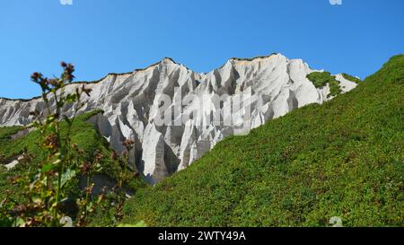 Erstaunliche weiße Berge mit grünem Gras. Clip. Wunderschöne Muster auf felsigen weißen Bergen mit hellem Grün an sonnigen Sommertagen. Weiße Steine von Stockfoto