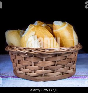 Frisch gebackenes Brot in einem Korb auf einer blau-weiß gestreiften Tischdecke Stockfoto