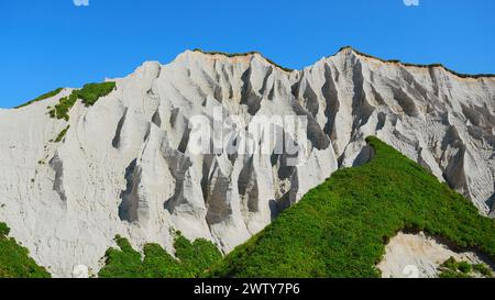 Erstaunliche weiße Berge mit grünem Gras. Clip. Wunderschöne Muster auf felsigen weißen Bergen mit hellem Grün an sonnigen Sommertagen. Weiße Steine von Stockfoto