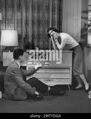 Gut gekleideter Junge und Mädchen im Wohnzimmer eines Hauses, hören Musik auf der Konsole Stockfoto