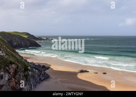 Ein dramatischer Blick auf Durness Beach in Schottland, wo zerklüftete Klippen auf den unberührten Sand und die smaragdgrünen Wellen des Atlantiks treffen Stockfoto