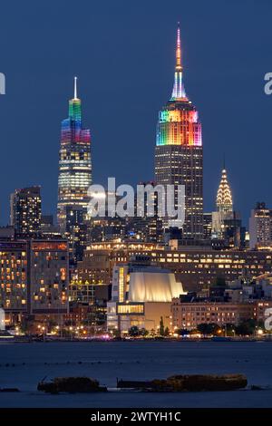 New York City: Das Empire State Building und ein in Regenbogenfarben beleuchtetes Venderbilt-Wolkenkratzer für die LGBTQ+ Gay Pride Week. Midtown, Manhattan Stockfoto