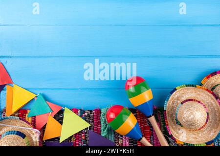 Mexikanischer Feiertagshintergrund mit einer Decke oder einem Poncho, Sombrero-Hut, Maracas auf einem alten blauen Holzhintergrund. Mexiko Cinco de Mayo Festival, Mexi Stockfoto