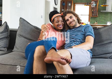 Ein vielseitiges Paar teilt sich einen gemütlichen Moment auf einem Sofa zu Hause Stockfoto