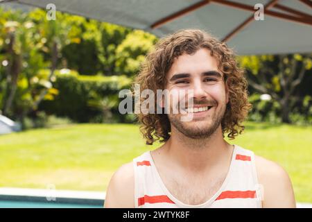 Ein junger Kaukasier mit lockigen Haaren lächelt im Freien Stockfoto