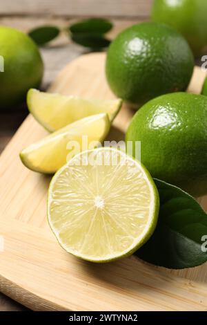 Ganz und frisch geschnittene Limetten auf Holzbrett, Großaufnahme Stockfoto