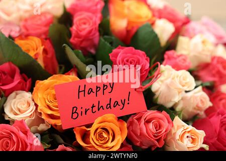 Blumenstrauß mit schönen Rosen mit Happy Birthday Karte, Nahaufnahme Stockfoto