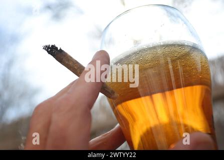 ILLUSTRATION - 20. März 2024, Bayern, Kaufbeuren: Eine Hand hält einen Joint neben einem Glas Bier. Der Bundestag verabschiedete die kontrollierte Freilassung am 1. April. Die Entscheidung des Bundesrates steht jedoch noch aus. Für die umstrittene Legalisierung von Cannabis am kommenden Freitag, den 22. März, gibt es im Bundesrat noch keine klare Mehrheit. Foto: Karl-Josef Hildenbrand/dpa Stockfoto