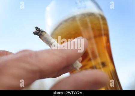 ILLUSTRATION - 20. März 2024, Bayern, Kaufbeuren: Eine Hand hält einen Joint neben einem Glas Bier. Der Bundestag verabschiedete die kontrollierte Freilassung am 1. April. Die Entscheidung des Bundesrates steht jedoch noch aus. Für die umstrittene Legalisierung von Cannabis am kommenden Freitag, den 22. März, gibt es im Bundesrat noch keine klare Mehrheit. Foto: Karl-Josef Hildenbrand/dpa Stockfoto