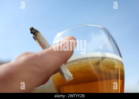 ILLUSTRATION - 20. März 2024, Bayern, Kaufbeuren: Eine Hand hält einen Joint neben einem Glas Bier. Der Bundestag verabschiedete die kontrollierte Freilassung am 1. April. Die Entscheidung des Bundesrates steht jedoch noch aus. Für die umstrittene Legalisierung von Cannabis am kommenden Freitag, den 22. März, gibt es im Bundesrat noch keine klare Mehrheit. Foto: Karl-Josef Hildenbrand/dpa Stockfoto