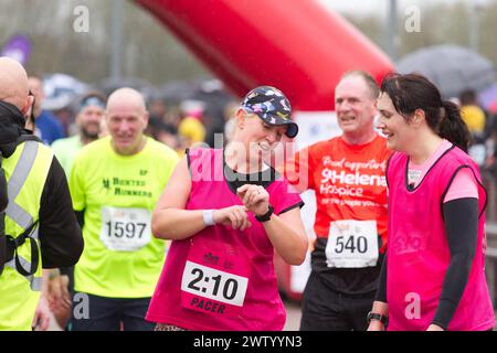 Läufer nach Abschluss des Halbmarathons in Colchester 2024. Der Lauf dient der Unterstützung des Robin Cancer Trust. Ein Pacer überprüft die Zeit nach dem Rennen Stockfoto