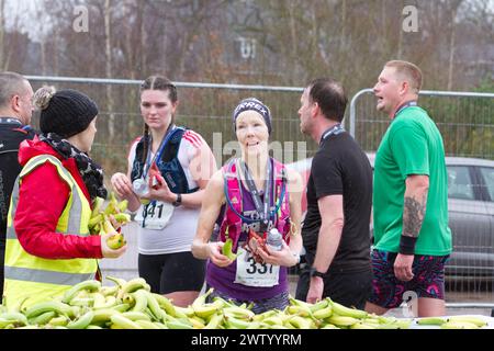Läufer nach Abschluss des Halbmarathons in Colchester 2024. Der Lauf dient der Unterstützung des Robin Cancer Trust. Läuferinnen mit Snacks zum Auftanken. Stockfoto