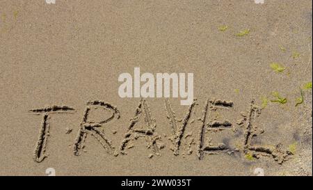 Reisekonzept - Beschriftung im Sand. Sandige Küste des Meeres. Motivation. Meereswelle. Das Wort Reisen steht am Strand. Urlaub am Th Stockfoto