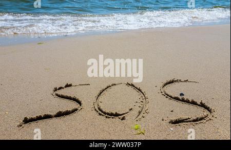 Die Inschrift auf dem Sand am Strand sos. Stockfoto