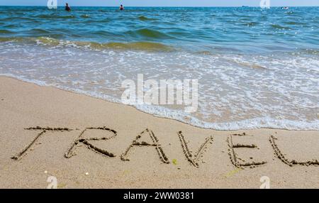 Reisekonzept - Beschriftung im Sand. Sandige Küste des Meeres. Motivation. Meereswelle. Das Wort Reisen steht am Strand. Urlaub am Th Stockfoto