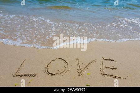 Inschrift Liebe auf den Sand gemalt. Konzept wahrer und ehrlicher romantischer Gefühle. Spa-Roman am Meer. Stockfoto