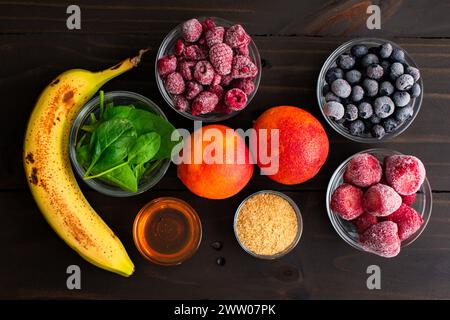Blood Orange Mixed Berry Smoothie Zutaten: Gefrorene Himbeeren, Erdbeeren und Heidelbeeren mit frischem Babyspinat, Banane und mehr Stockfoto