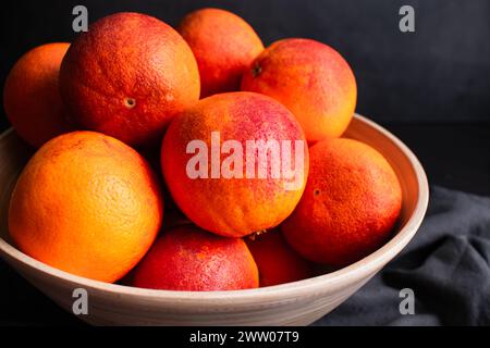 Seitenansicht der Blutorangen in einer Schüssel: Mehrere ganze Himbeerorangen in einer großen Schüssel aus Bambusholz Stockfoto