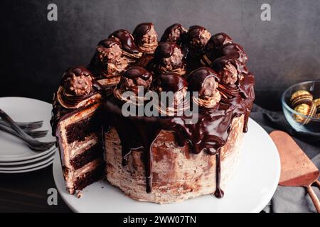 Haselnussschokolade-Kuchen mit Schokoladenganache und Haselnussbonbons: Schokoladenschicht-Kuchen mit Haselnussbuttercreme-Frosting im Aquarelleffekt Stockfoto