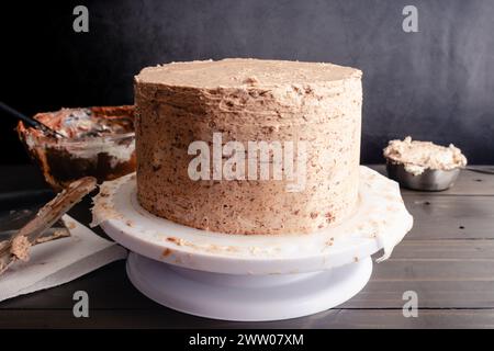 Schokoladenkuchen-Crumb-überzogen mit Haselnuss-Buttercreme-Zuckerguss: Schicht Kuchen mit Haselnuss-Buttercreme-Zuckerguss auf einem Kuchenständer Stockfoto