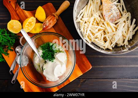 Zitronensauce in einer Glasmischschale herstellen: Saure Cremesauce mit saftigen Zitronen und einer Schüssel SelleriewurzelRemoulade Stockfoto