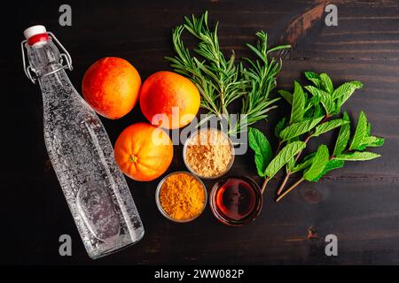 Blood Orange Mocktail Zutaten auf dunklem Holzhintergrund: Sprudelwasser, Blutorangen und Honig mit frischen Gewürzen auf einem Tisch Stockfoto