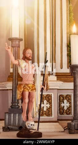 Eine Holzfigur Jesu von einem unbekannten Autor in einer Kirche neben brennenden Kerzen. Stockfoto