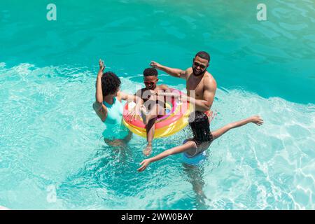 Eine afroamerikanische Familie genießt einen sonnigen Tag im Pool, türkisfarbenes Wasser glitzert Stockfoto