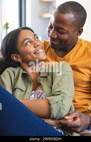 Ein vielseitiges Paar teilt sich einen zärtlichen Moment zu Hause auf der Couch Stockfoto