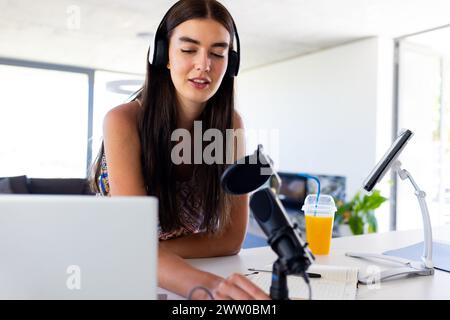 Eine junge weiße Brünette nimmt zu Hause einen Podcast auf Stockfoto