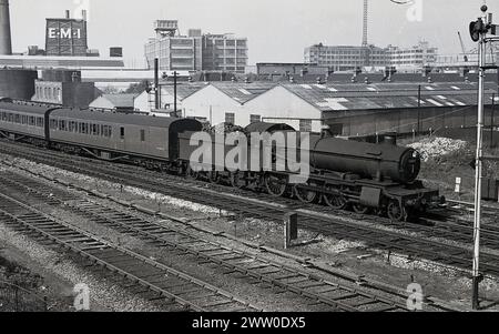 1950er Jahre, historische Dampflokomotive der Briitsh Railways, 6864, Dymock Grange, auf der Bahnstrecke, mit Kohlewagen und Wagen, England, Großbritannien. Die 4-6-0-Lokomotive der Great Western Railways (GWR) wurde 1939 gebaut und dem Schuppen in Old Oak Common zugeordnet. 1947 wurde sie Reading und 1955 nach Oxford versetzt. 1965 wurde sie aus dem Dienst genommen und im folgenden Jahr abgesetzt. Stockfoto