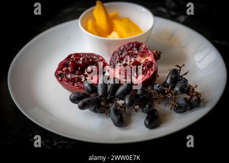 Ein Teller mit farbenfrohen und frischen Früchten. Die lebendige Mischung aus Farben und Texturen ist optisch ansprechend. Stockfoto
