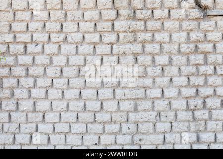 Handgefertigte graue Ziegelsteinmauertextur mit natürlichen Einschlüssen von Muscheln und Wurzeln in einem ländlichen Küstenhaus. Rustikale Architektur Stockfoto