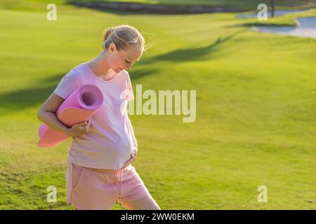 Eine schwangere Frau, die ihr Workout im Freien macht, verwendet eine Trainingsmatte für eine erfrischende und gesundheitsbewusste Outdoor-Trainingseinheit Stockfoto