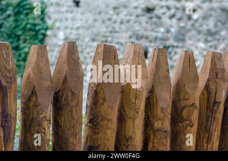 Holzzaun, für Gärten am Straßenrand, mit langen runden Stangen. Hintergrund mit Holzmotiven, mit Stämmen, die gegen Regen und atmosphärische Einflüsse geschützt sind. Stockfoto